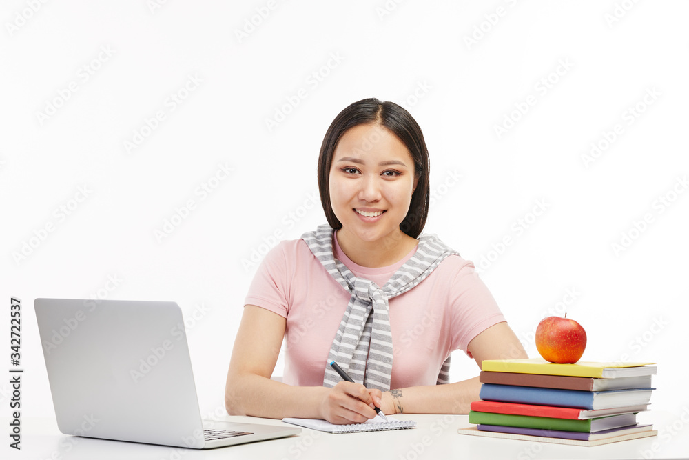 Young college student poses at the camera as she sits at the table. Young college student poses at the camera as she sits at the table.