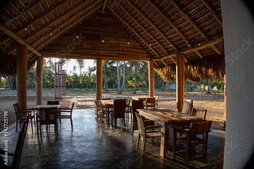 Wide angle view of a tropical beach club restaurant, still empty, in the golden sun light of the sunrise. Peaceful, quiet place.