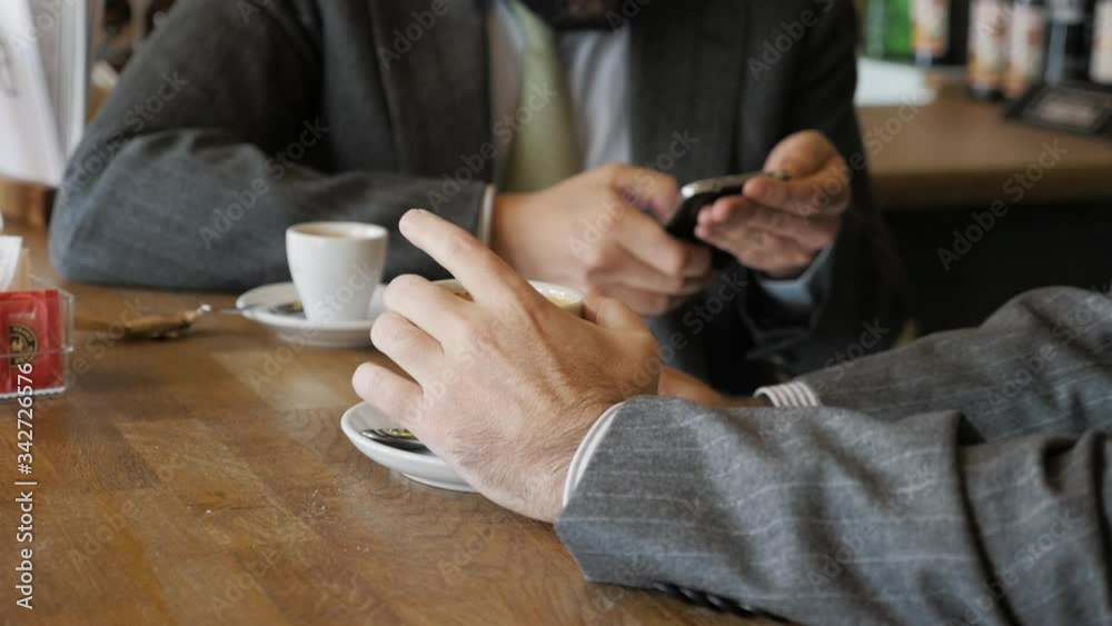Entrepreneurs drinking coffee and checking their cell phones Entrepreneurs drinking coffee and checking their cell phones
