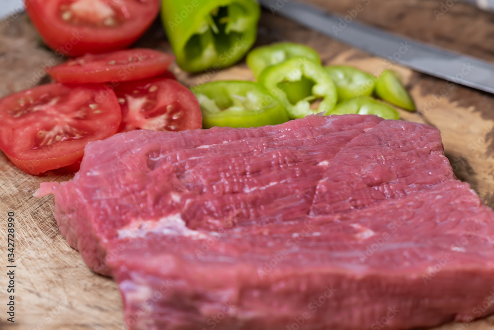 sliced tomatoes, sliced peppers, beef fillet on a wooden background
