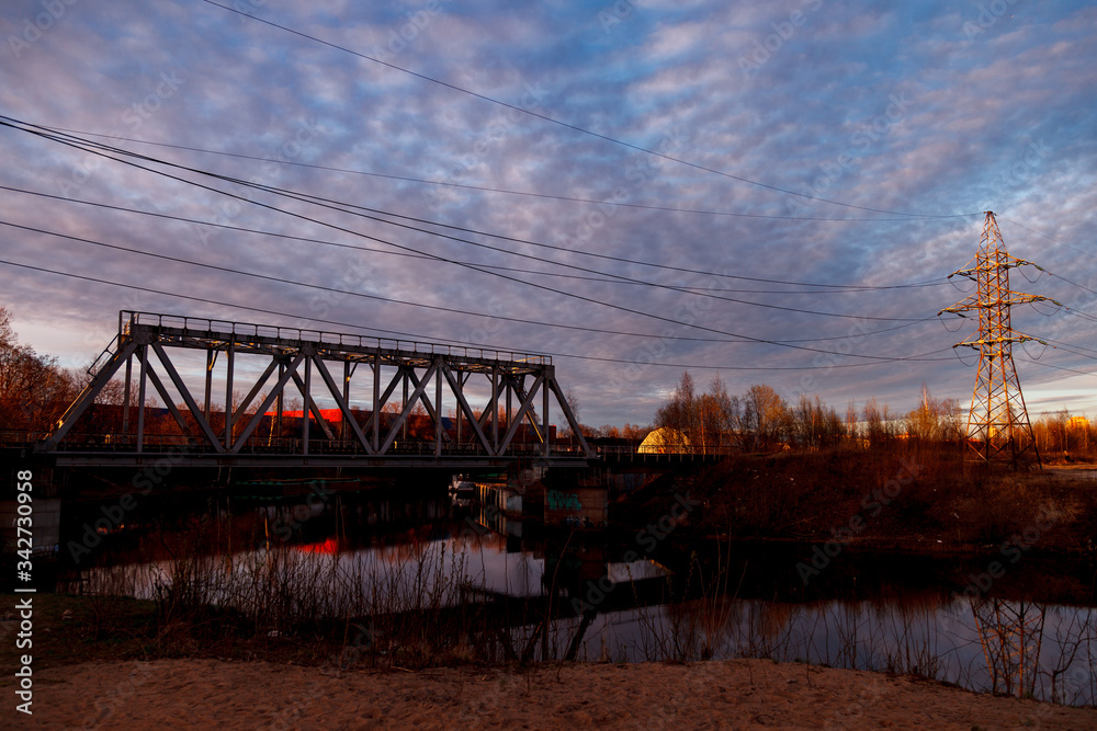 Railway bridge over the river and high-voltage power lines in the industrial zone of the city