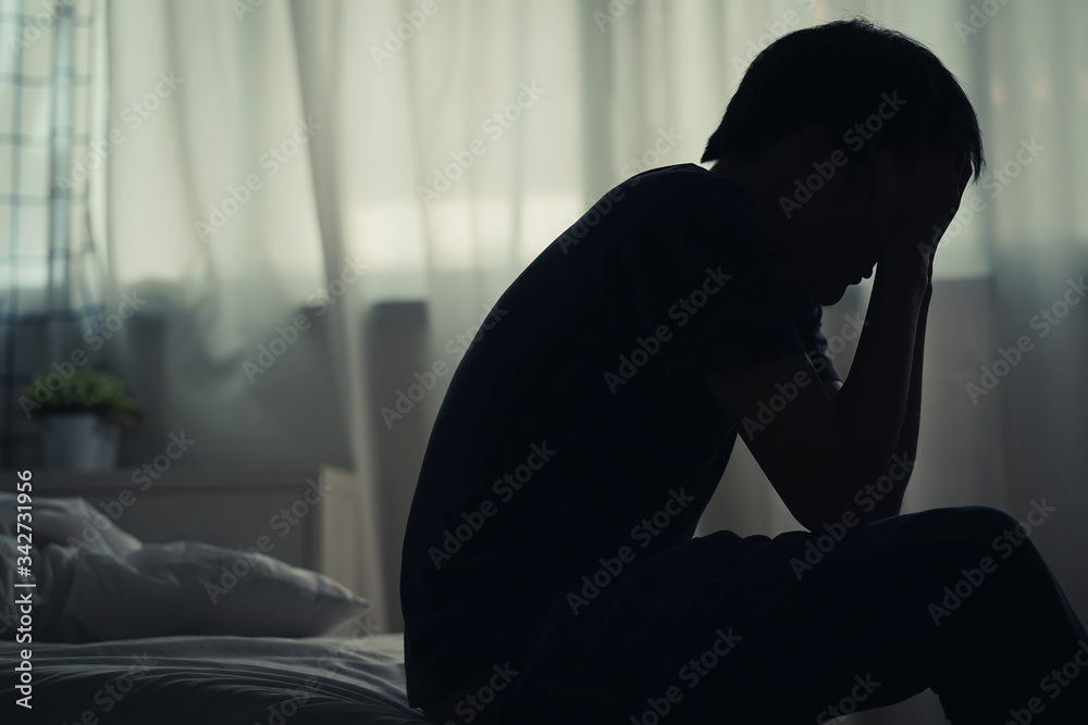 Depressed lonely man sitting alone on the bed with hands on head feel  stress, sad and worried in the dark bedroom and low light environment.  Stock Photo | Adobe Stock