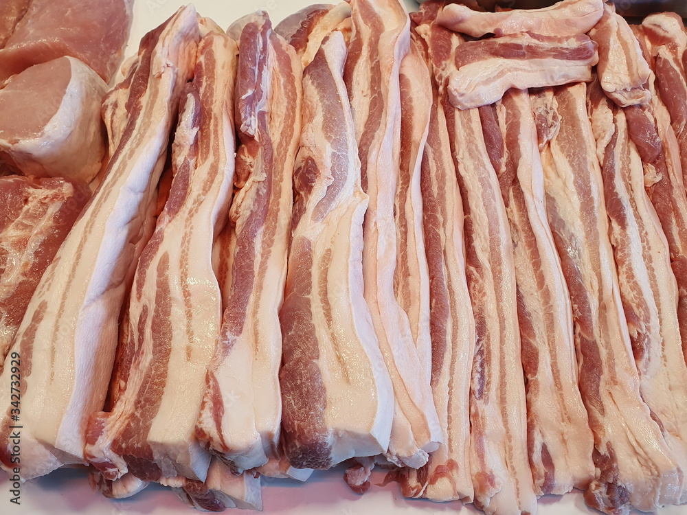 Organic streaky pork cut into long strips and placed at a shop in the fresh food market. Pork belly contains nutrients, proteins and fats that are needed to repair the wear and tear of the body.
