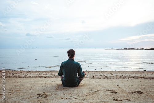 Young man meditating on the beach