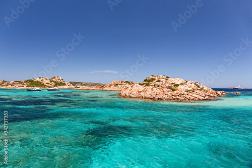 Panoramic view of the pink granite rock formations and the clear and transparent waters in the Maddalena archipelago in Sardinia, Italy. © serghi8