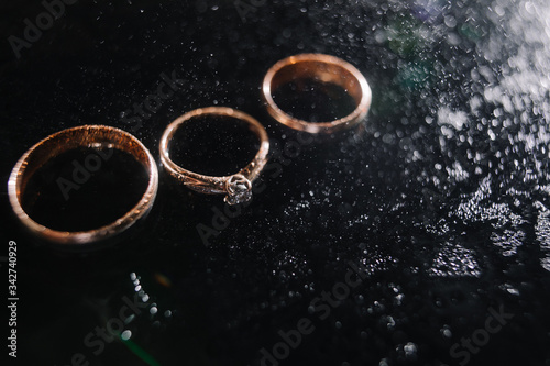 wedding rings in spray of water. golden rings in a dark key. engagement ring. selection of rings for marriage.