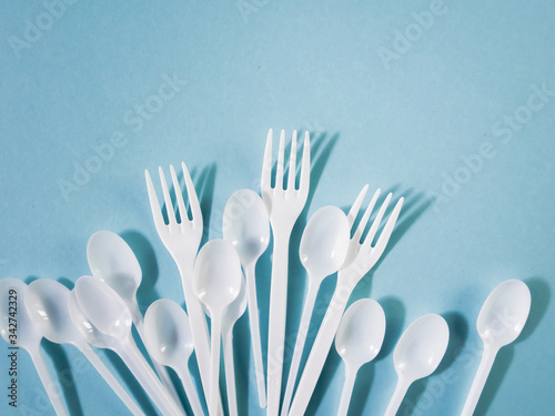 Plastic dishes, disposable tableware, plates, glasses, spoons, forks on a blue background. Caring for the environment. The problem is recycling. Reuse, safe planet, environmental concept. Trash.