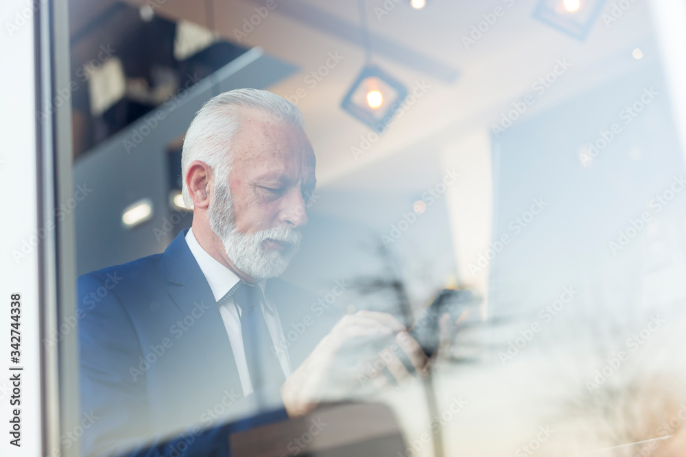 Fototapeta premium Senior businessman sending an email using smart phone