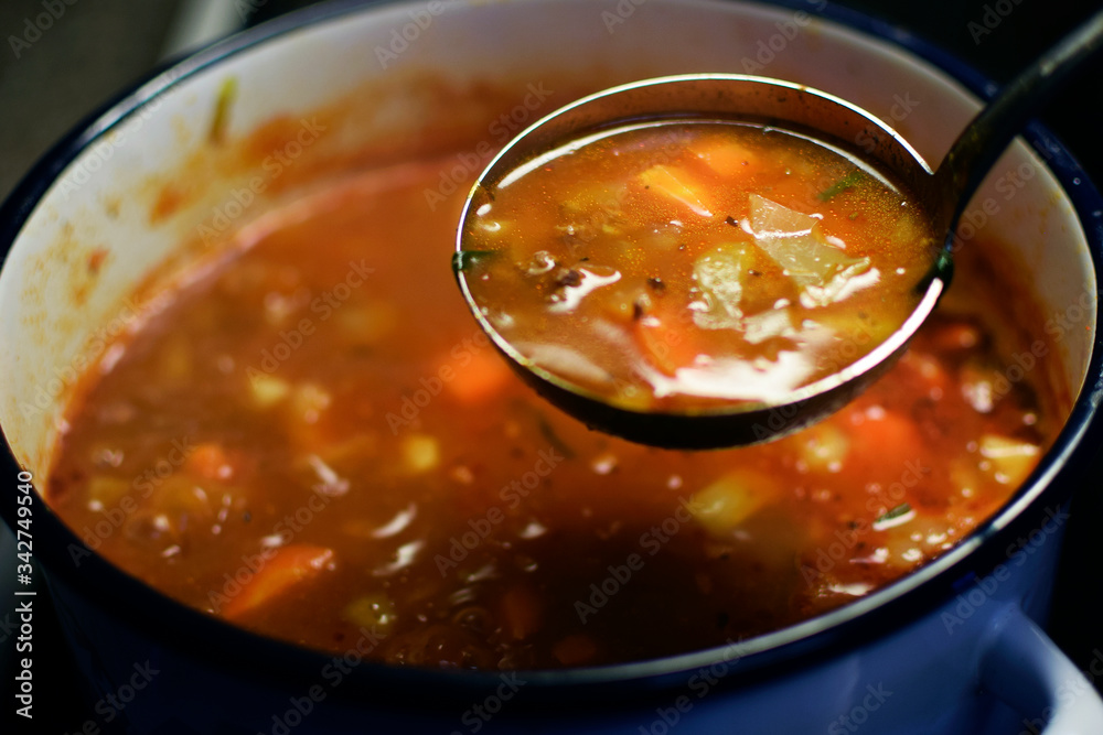Cabbage soup. Blurred cooking pot on background. Focus in ladle. Cabbage soup. Blurred cooking pot on background. Focus in ladle.