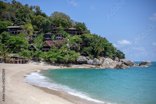 Small houses on the mountain on the beach in Thailand on the island of Koh Phangan. Background with white sand and blue sea.