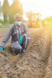 Female farmer  analyses the soil before planting and wearing a protective mask against coronavirus