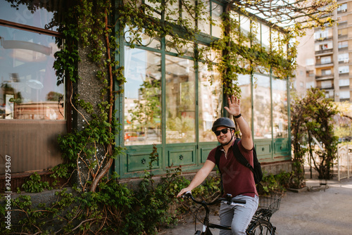 Young caucasian cyclist with helmet and sunglasses on a bicycle in front of the window photo