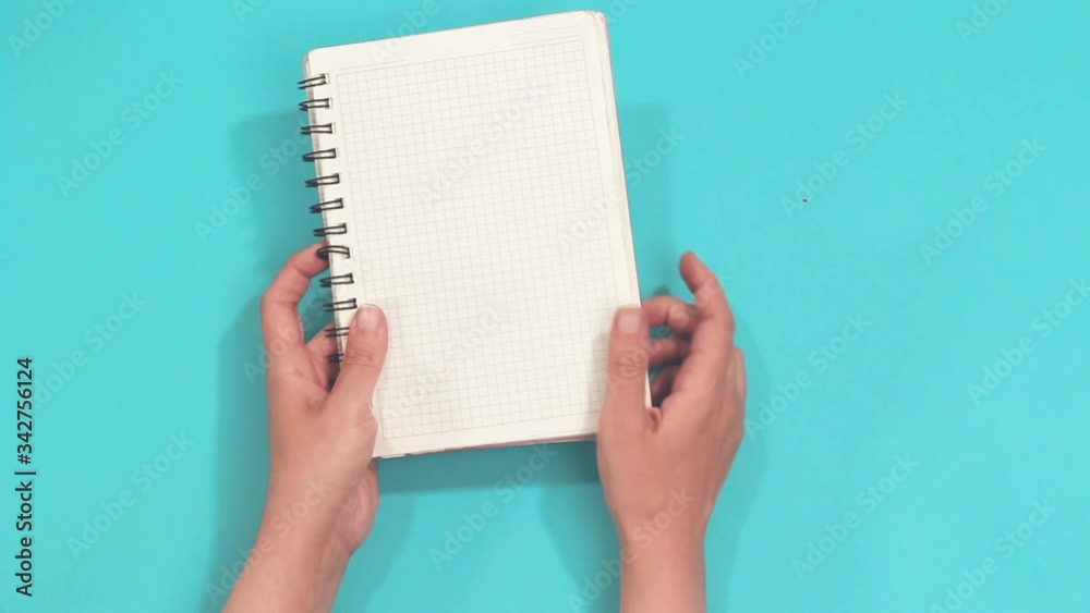 hands holding empty notebook isolated on blue 