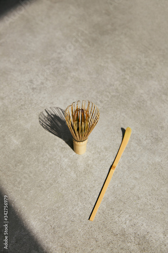 Bamboo whisk and chashaku bamboo spoon for matcha tea on a gray stone surface.