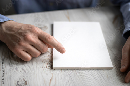 Men's hands in a blue office shirt point to a blank notebook on the table. Concept - work in the office.