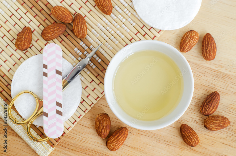 Small white bowl with almond oil, scissors and nail file for natural nails and cuticle treatment. Homemade manicure and pedicure concept. Top view, opy space. Small white bowl with almond oil, scissors and nail file for natural nails and cuticle treatment. Homemade manicure and pedicure concept. Top view, opy space.