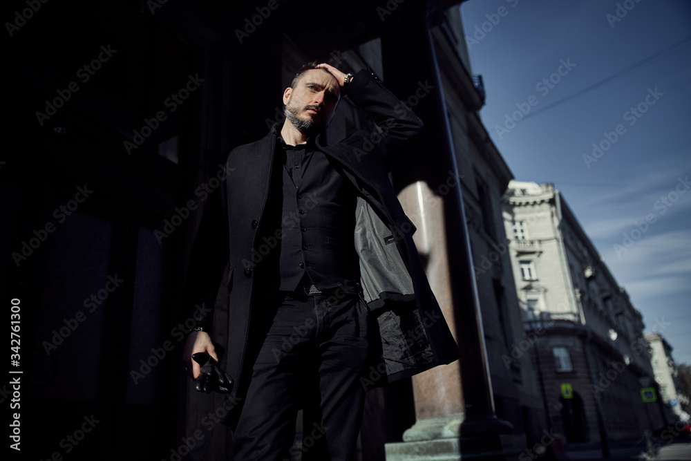 a man in a black suit walks along the historical streets of the city
