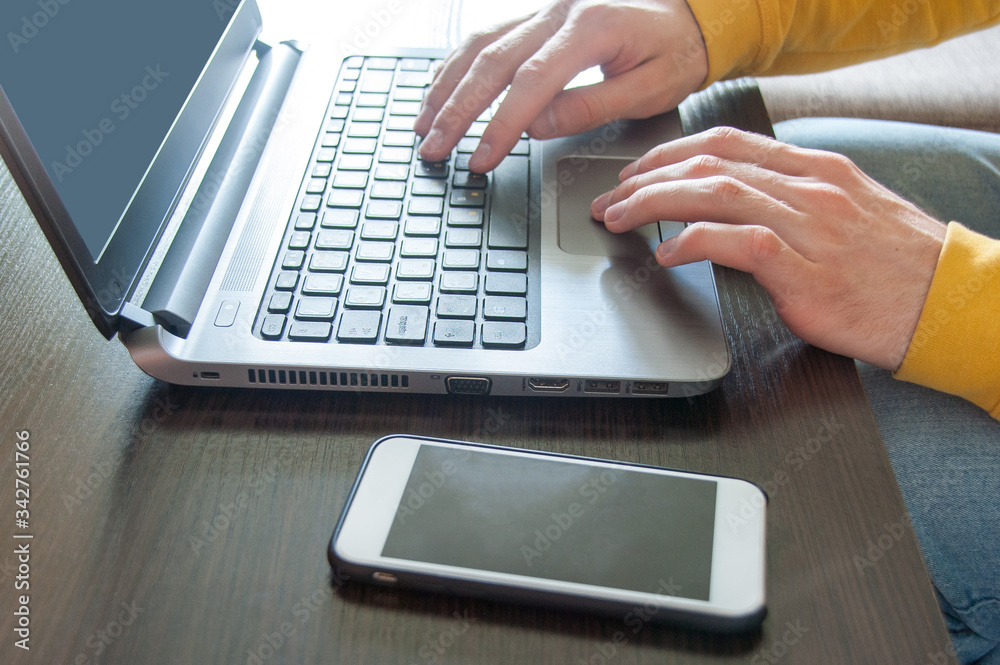 Close up of hand businessman or student typing on the keyboard working on a laptop at home. Smartphone lying in front of the pc. Freelancer concept. Work from home Close up of hand businessman or student typing on the keyboard working on a laptop at home. Smartphone lying in front of the pc. Freelancer concept. Work from home