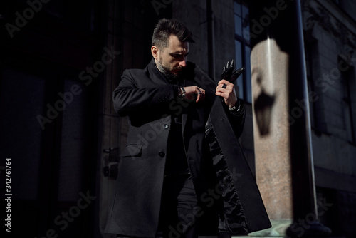 a man in a black suit walks along the historical streets of the city