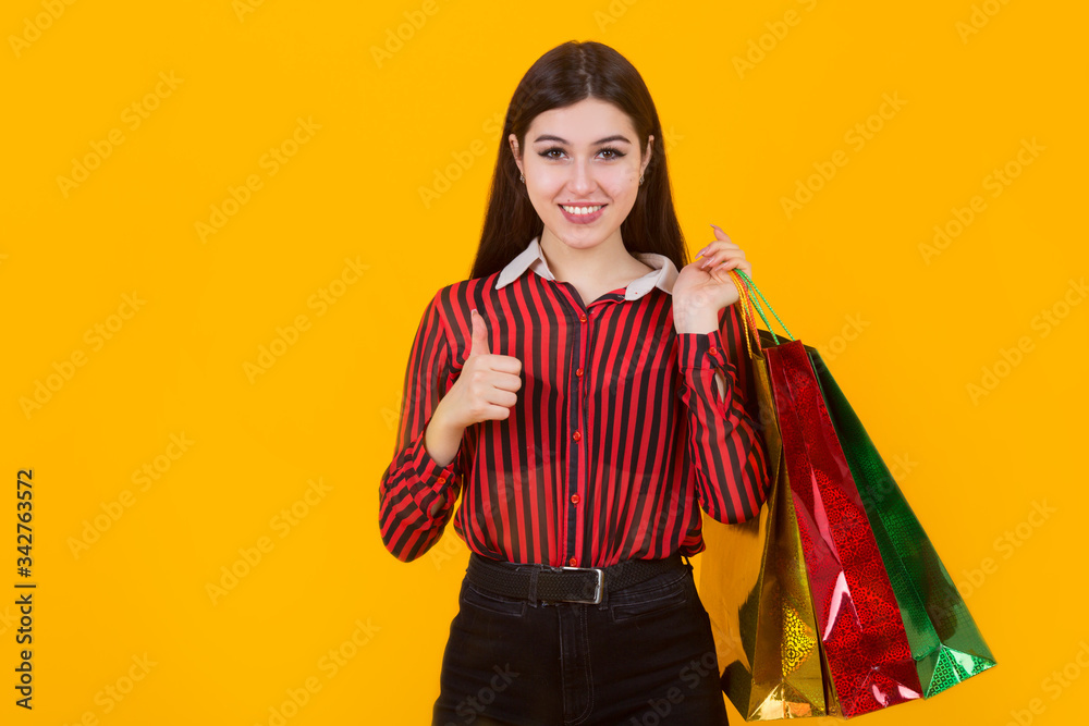beautiful young woman with packages in hands on a yellow background
beautiful young woman with packages in hands on a yellow background