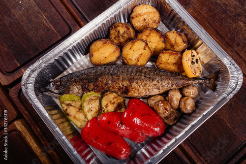 Appetizing mackerel fish baked on fire with spices, served on a plate and decorated with vegetables photo