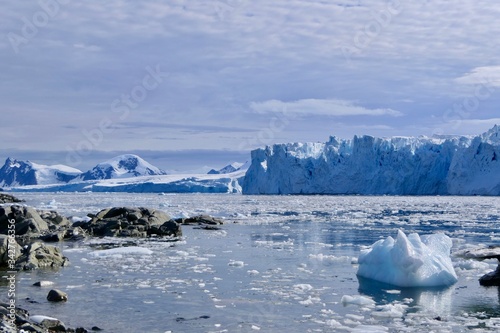 Glacier front with ice floes before water in Antarctica, blue sky and clouds, Stonington Island