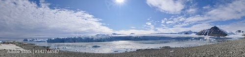 People on winter stone beach landscape with glacier front, ice floes and mountains and in Antarctica, Stonington Island