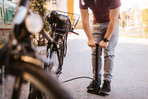 Handsome young caucasian man pumps a bicycle tire