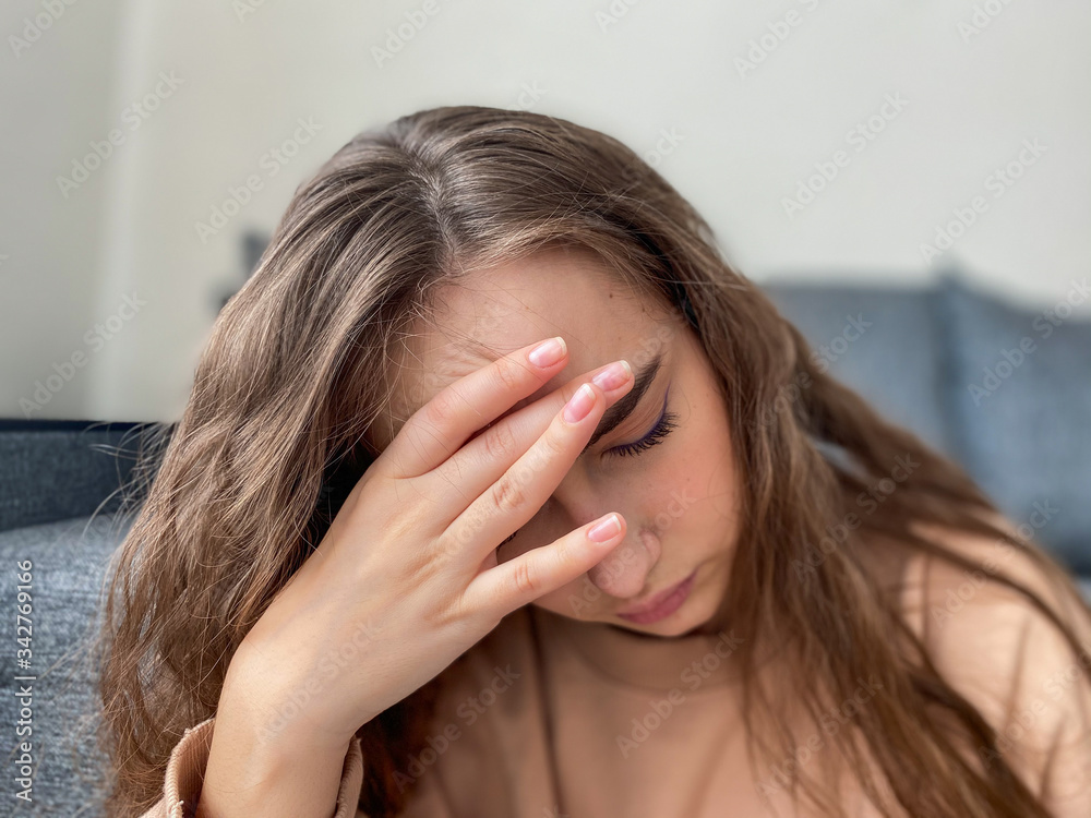 Depression a young woman with long hair is sitting on the sofa in her living room. Depression a young woman with long hair is sitting on the sofa in her living room.