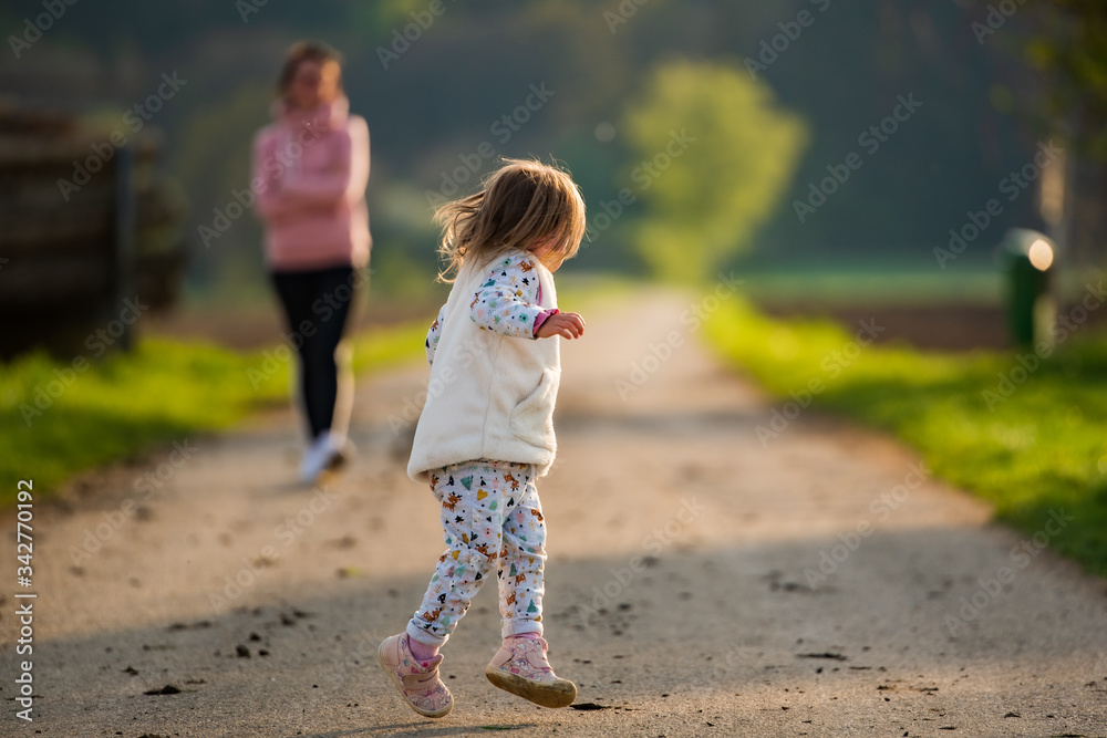 Mother and child walking on countryside road between agricultural fields towards vilage from forest Mother and child walking on countryside road between agricultural fields towards vilage from forest