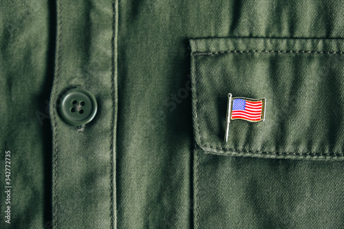 USA flag pin badge on green jacket pocket. Top view. Copy, empty space for text