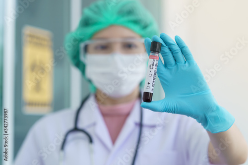 Doctor s hand holding a test tube with contaminated blood sample inside.