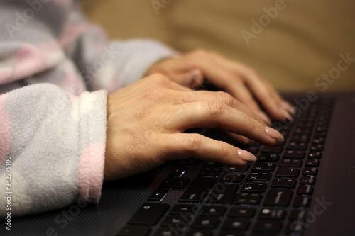 young woman in pajamas sitting on bed with laptop. Freelance business quarantine concept, remote work at home