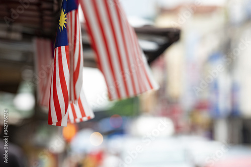 (Focus on the flags) View of some Malaysian national flags in the foreground and a blurred road in the background. The name of the national flag is Jalur Gemilang meaning 'Stripes of ExcellenceÕ.