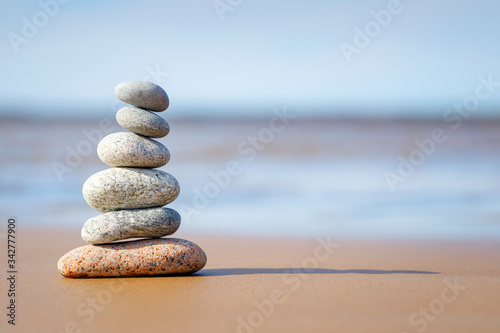 Pyramid stones balance on the sand of the beach. The object is in focus, the background is blurred.