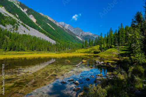 lake in mountain valley, surface of water under rocky peaks, mountain surface on horizon, path to top and its achievement by river