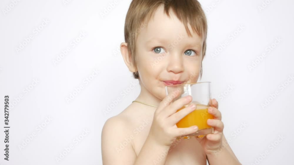 A beautiful naked boy drinks fresh orange juice from a glass A beautiful naked boy drinks fresh orange juice from a glass
