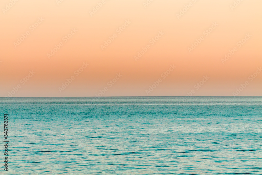 the orange Sunset over the calm blue ocean