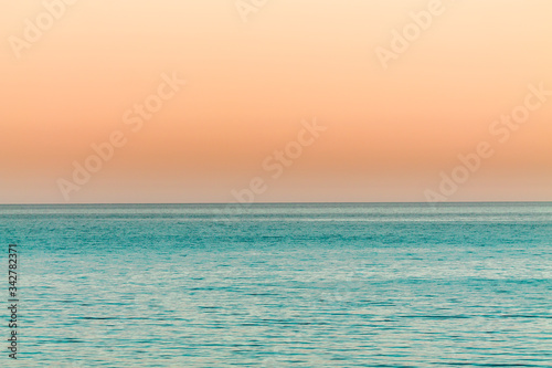 the orange Sunset over the calm blue ocean