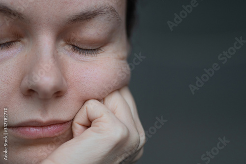 A bored woman rests her cheek on her hand, the creases