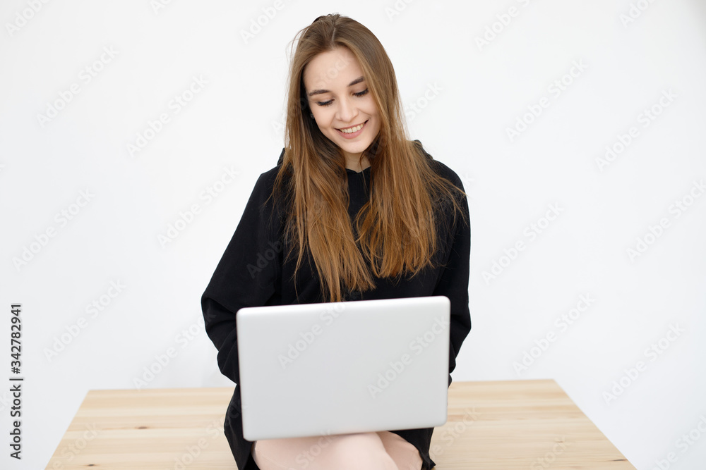 A young smiling girl a woman, undergoing distance learning. Freelancer, remote work at home, online training. A young smiling girl a woman, undergoing distance learning. Freelancer, remote work at home, online training.
