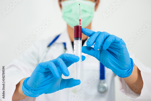 The doctor holds the syringe and the patient's blood sample for examination.