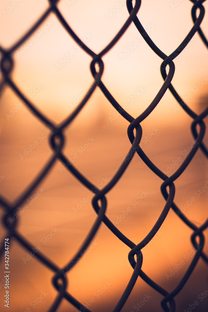 Naklejka premium Sunset behind chainlink fence