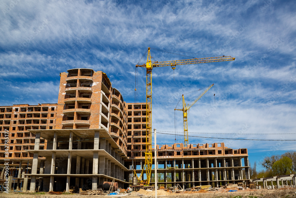 Work in progress on a new apartment block. Tall building under construction with cranes. Construction Site of New Building.
