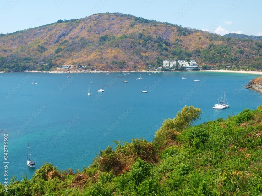 Panoramic view of bay. Tropical island Cote d'Azur. Bright turquoise water, green foliage on a shore. Yachts, boats in a quiet harbor. White buildings of the building on a hillside. Sea luxury resort.