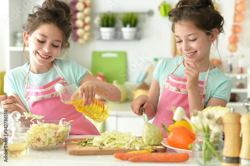 Cute girls preparing delicious fresh salad in kitchen
