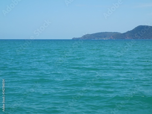 Seascape. Panoramic views of the horizon and the open ocean. A rocky cape extents to the depth sea. Blue sea. Turquoise water. Calm. Ripples on the surface of the water. Cruise. Island. Sea traveling.