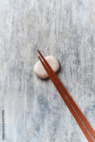 Wooden chopsticks and chopstick rest on rustic wooden background. Top view. Copy space.	
