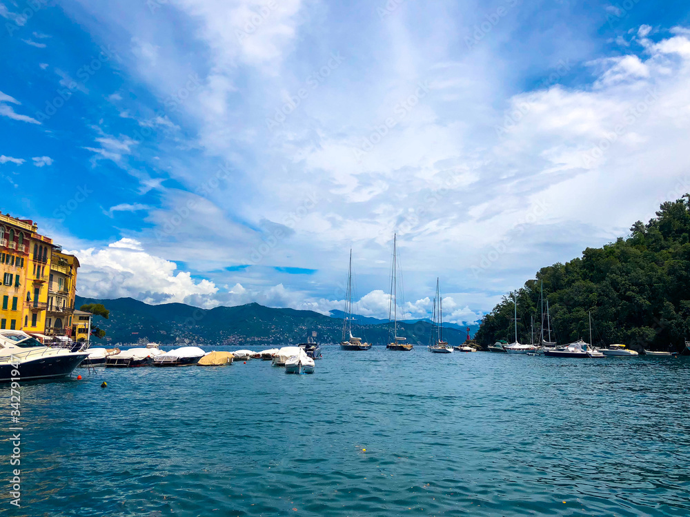 Wide panoramic view of Portofino, one of the world's most beautiful seaside towns on the Italian Riviera. Mediterranean landscape of yacht-filled harbor. ITALY - June, 2018.