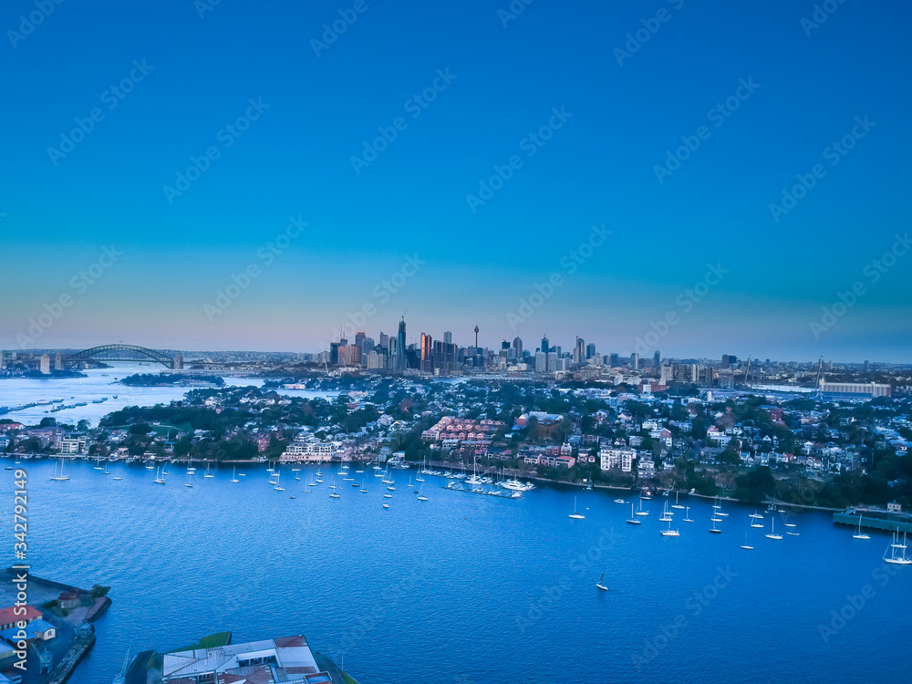 Panoramic drone aerial view over Sydney harbour on a cloudy sunset showing the nice colours of the harbour foreshore